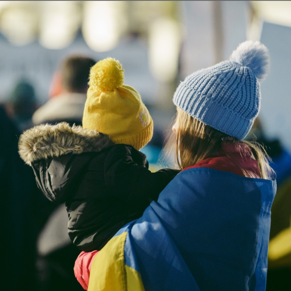 Mutter mit Kind auf dem arm, beide tragen eine Bommelmütze