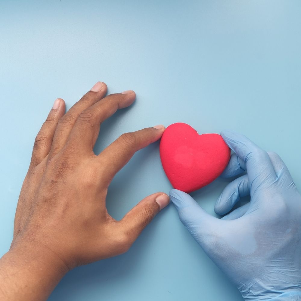 bild mit zwei händen, eine hand nimmt ein deko-herz entgegen von einer hand mit einem op handschuh zur repräsentativbefragung von hausärzten und hausärztinnen zum thema organ- und gewebeproben